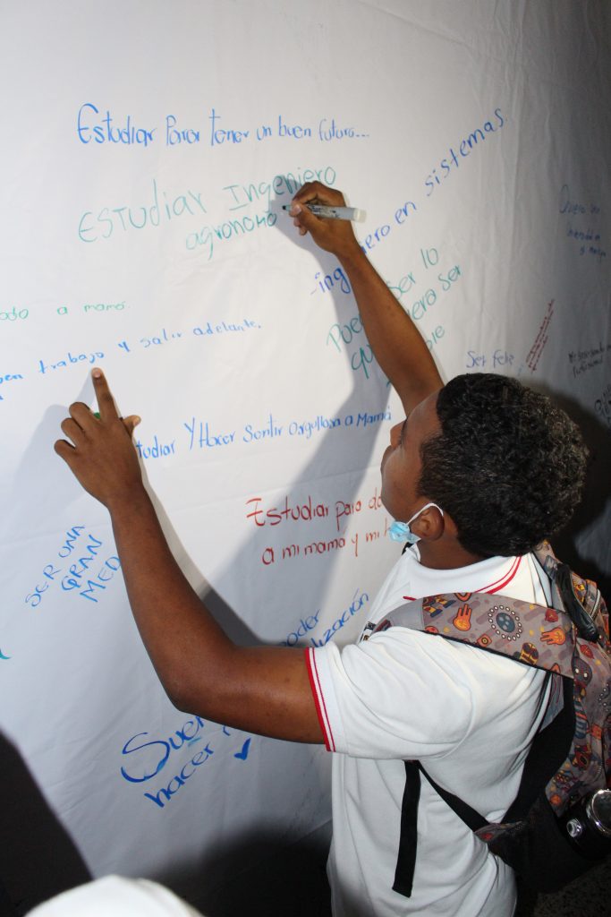 La Directora Ejecutiva (e) de la Corporación Gilberto Echeverri Mejía, un estudiante de La Pintada, y el Secretario de Educación de Antioquia, plasmando sus sueños. Estudiante escribiendo sus sueños